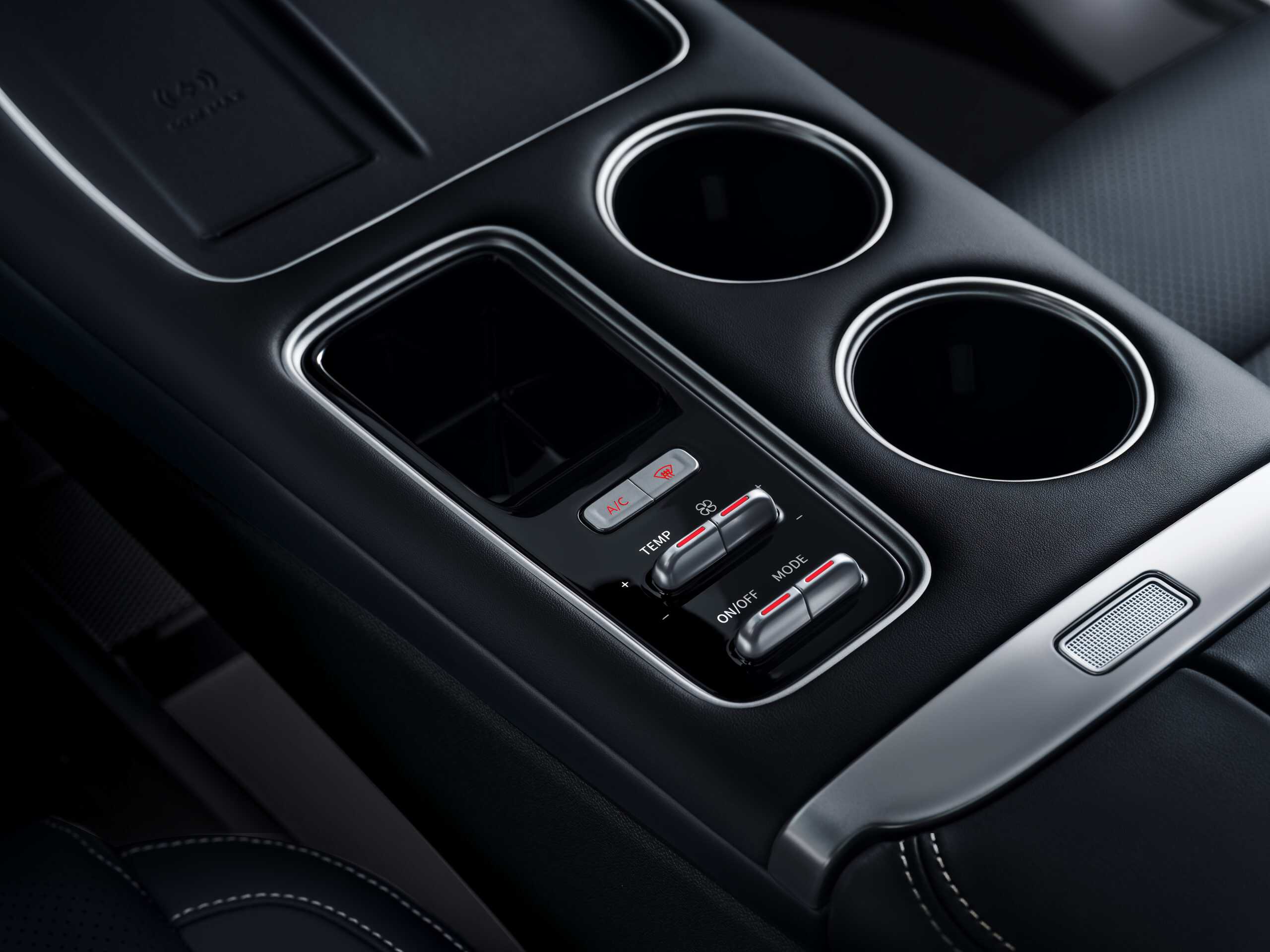 Close-up of a car's center console showing two circular cup holders and climate controls.