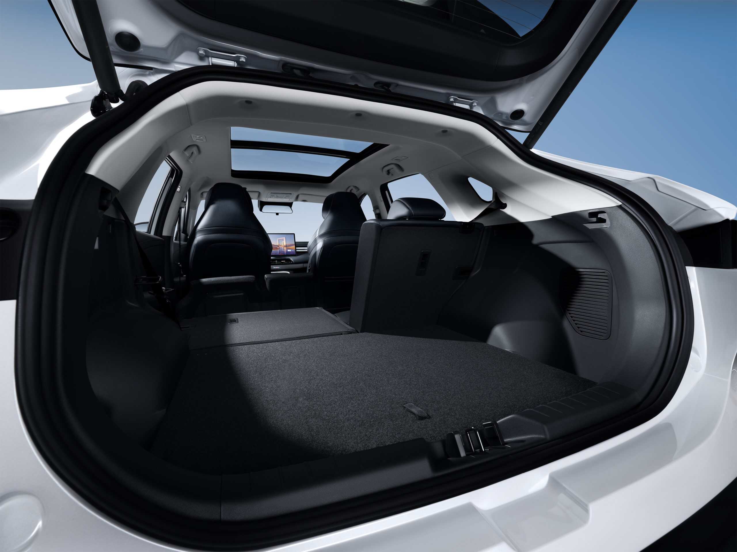Open SUV hatch shows a spacious cargo area with rear seats folded flat and a panoramic sunroof above.